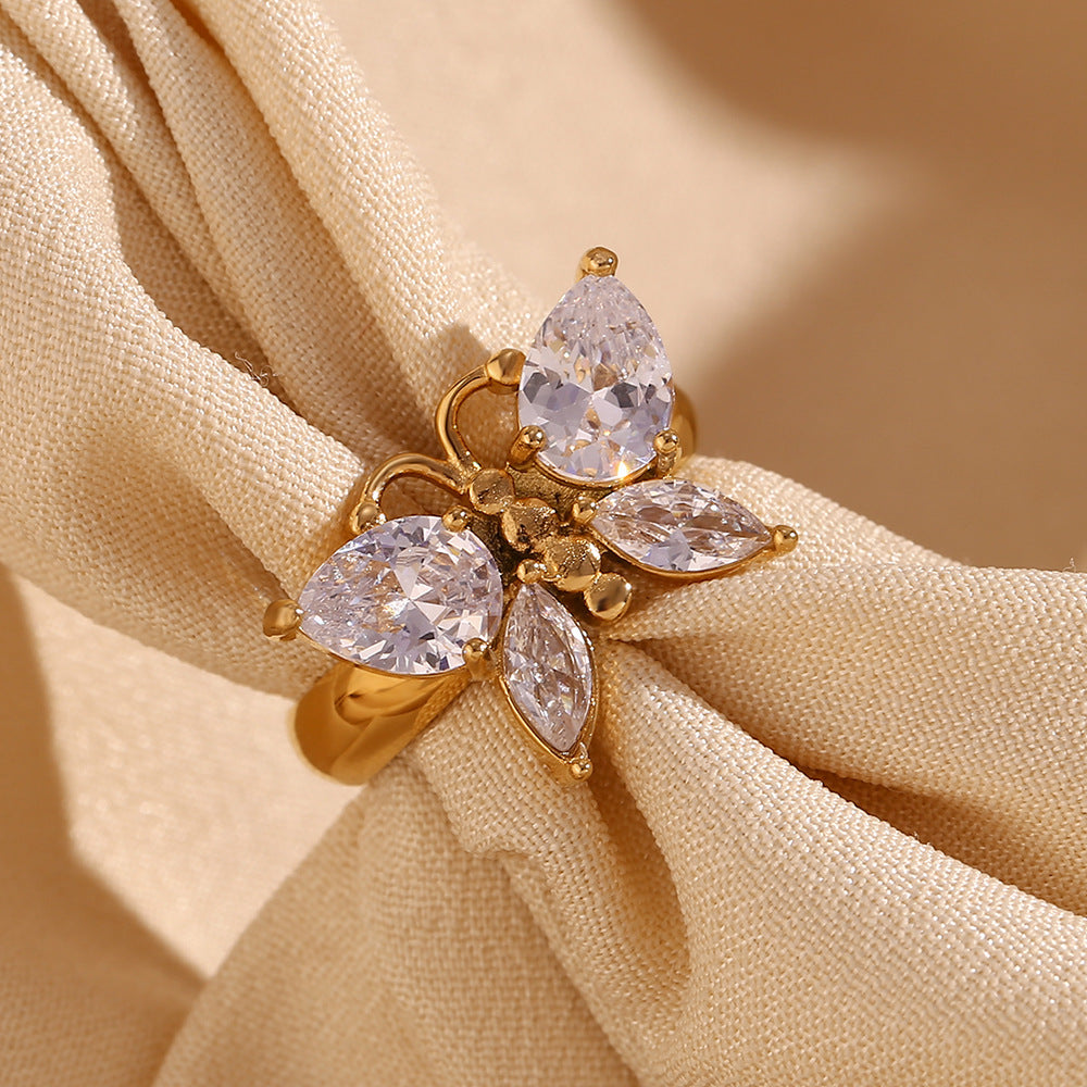 Gold ring with three pear-shaped gemstones on beige fabric