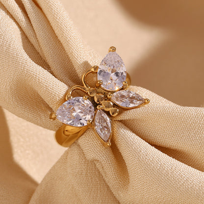 Gold ring with three pear-shaped gemstones on beige fabric
