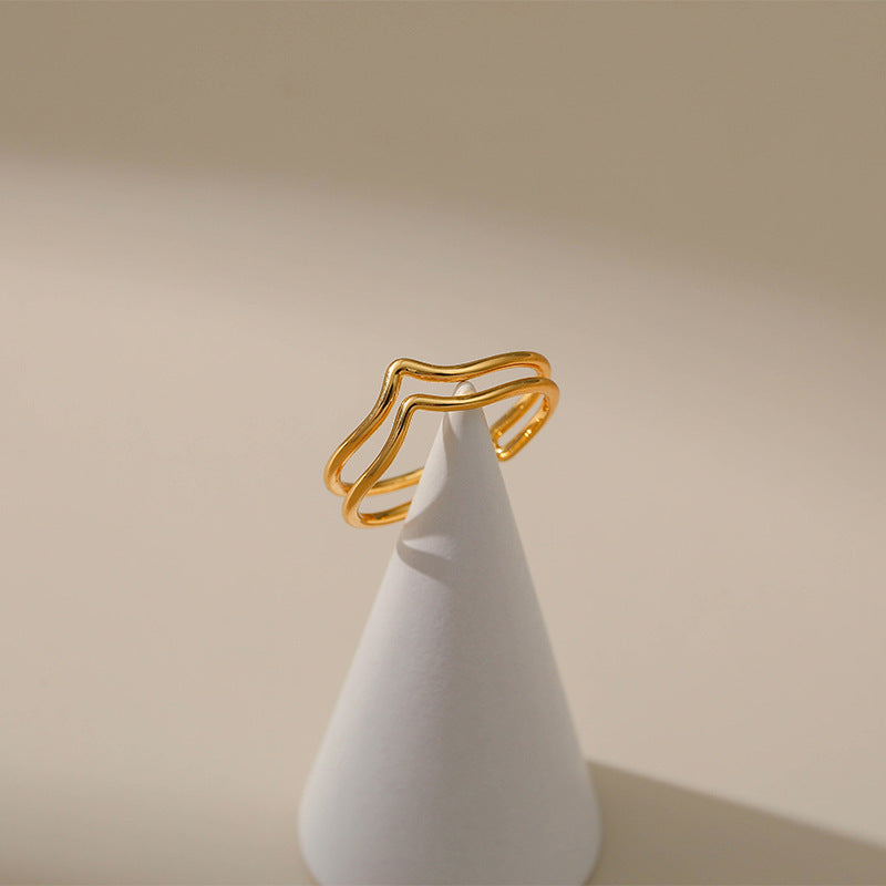 Gold ring on a white cone against a beige background
