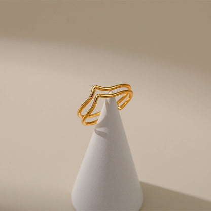 Gold ring on a white cone against a beige background