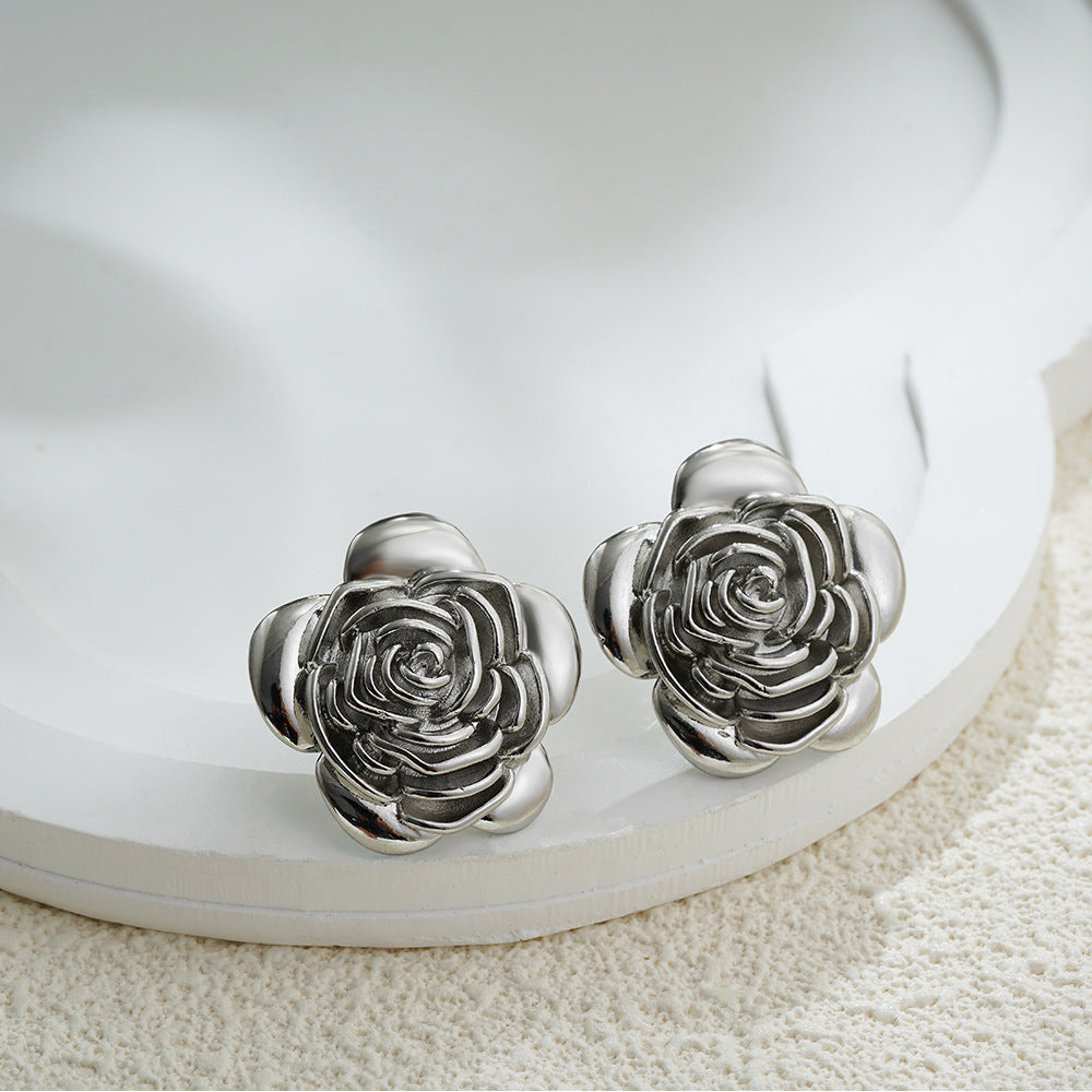 Silver rose-shaped earrings on a white dish