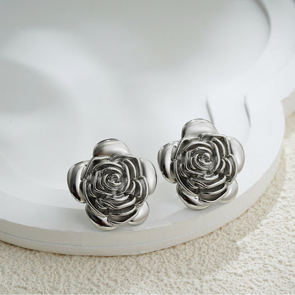 Silver rose-shaped earrings on a white dish