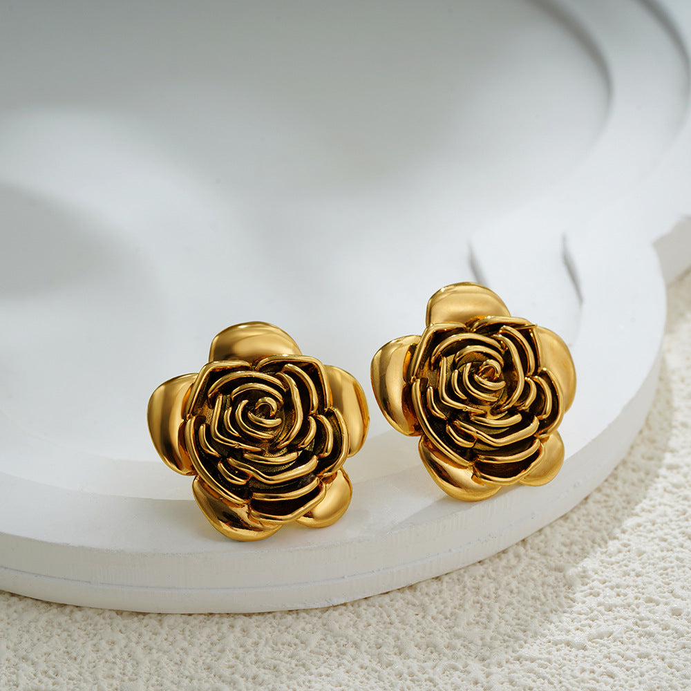 Gold rose-shaped earrings on a white surface