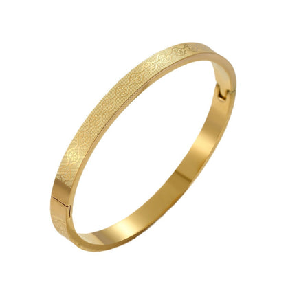 Gold bracelet with intricate patterns on a white background