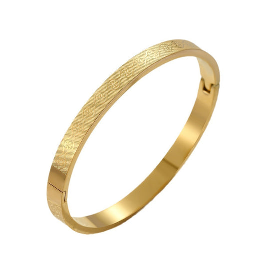 Gold bracelet with intricate patterns on a white background