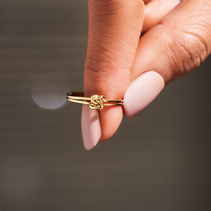 Gold floral ring with delicate petals, showcased flat on a crisp white background.