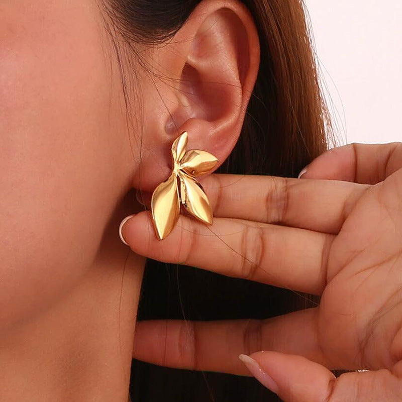 Gold leaf earring being worn and adjusted by a person.