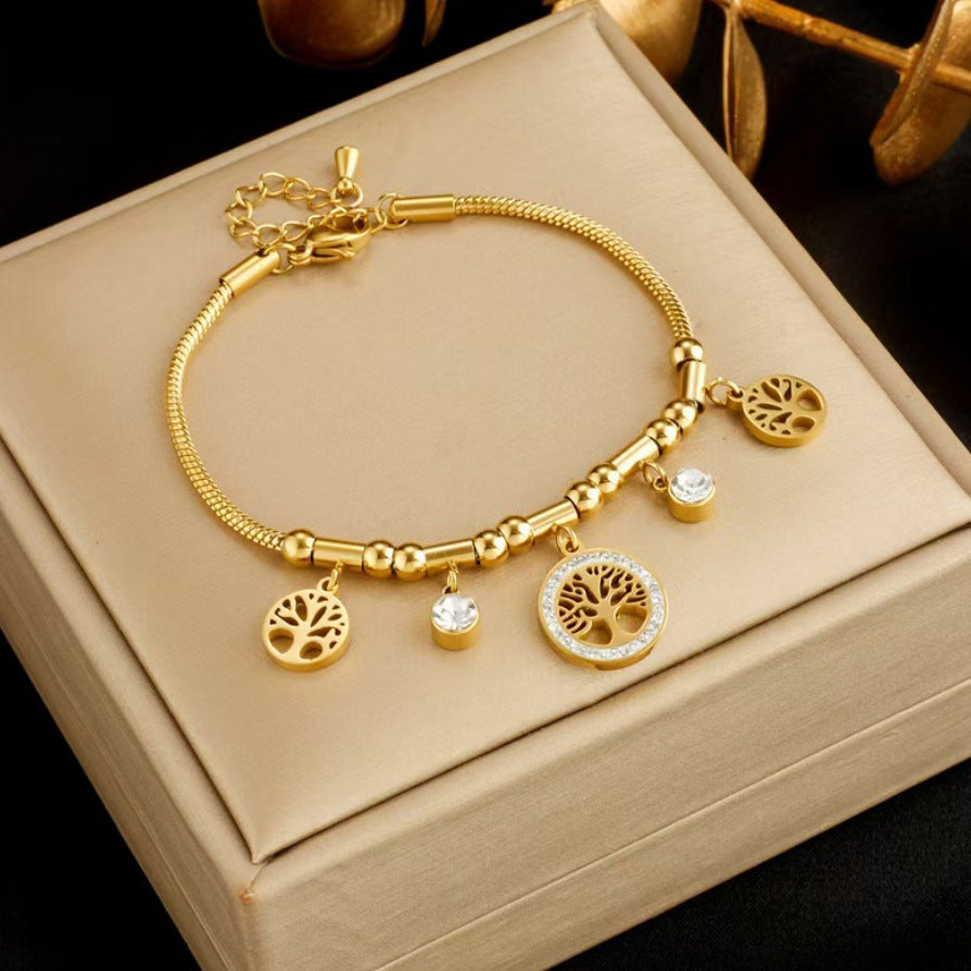 Gold bracelet with tree of life charms on a beige jewelry box