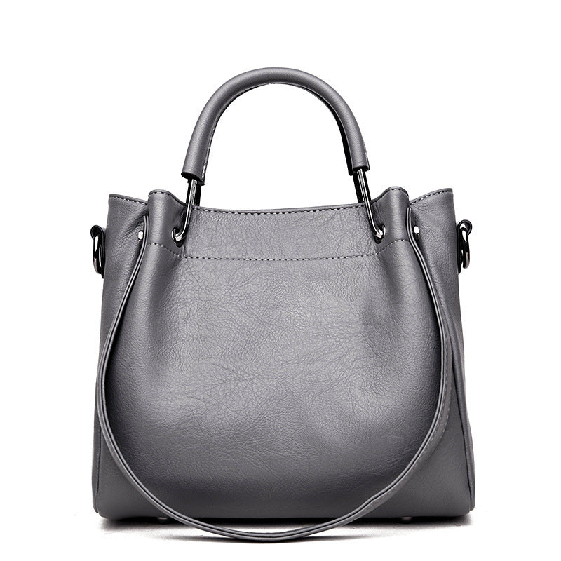 Women’s retro bucket handbag in soft leather with top handles and shoulder strap, available in multiple colours.