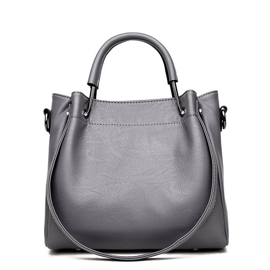 Women’s retro bucket handbag in soft leather with top handles and shoulder strap, available in multiple colours.