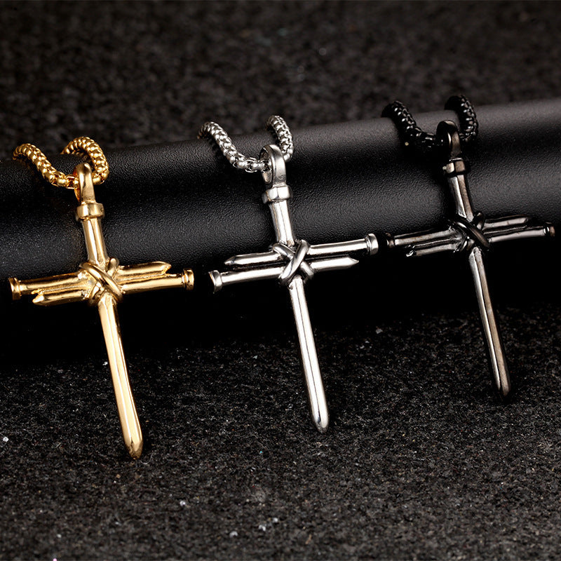 Three cross-shaped pendants in gold, silver, and bronze on a black background