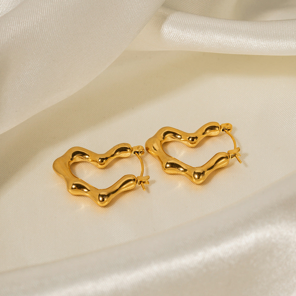 Gold heart-shaped hoop earrings on a white satin background