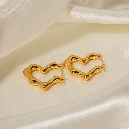 Gold heart-shaped hoop earrings on a white satin background