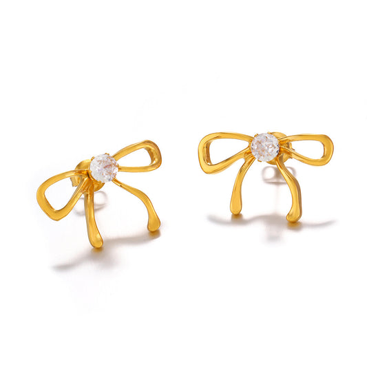 Gold bow-shaped earrings with clear gemstones on a white background
